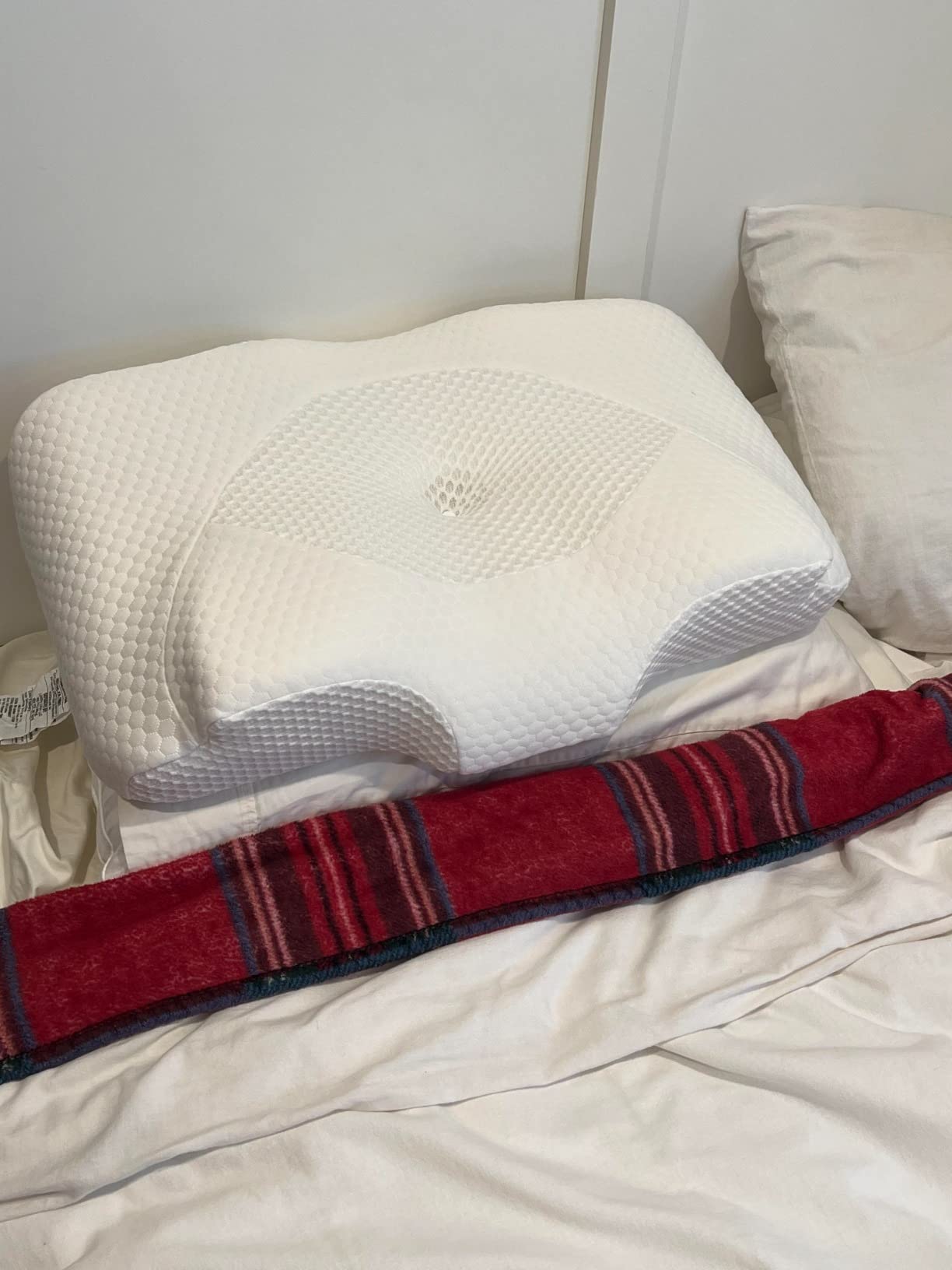 A Famedio Pillow for Back Stomach Sleeper rests on a bed with a cozy blanket, creating a comfortable sleeping space.