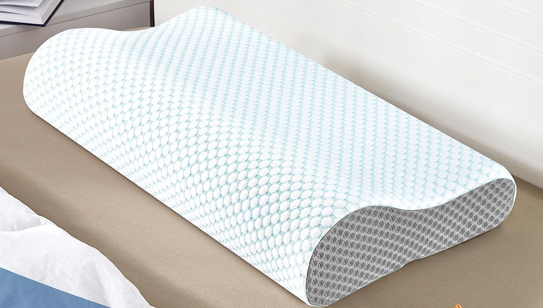 A blue and white patterned pillow, the Ergonomic Pillow for Neck, shown in use for a product review.