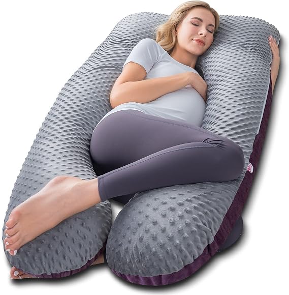 A woman relaxes on a large Meiz Pregnancy Pillow with her legs comfortably spread apart.