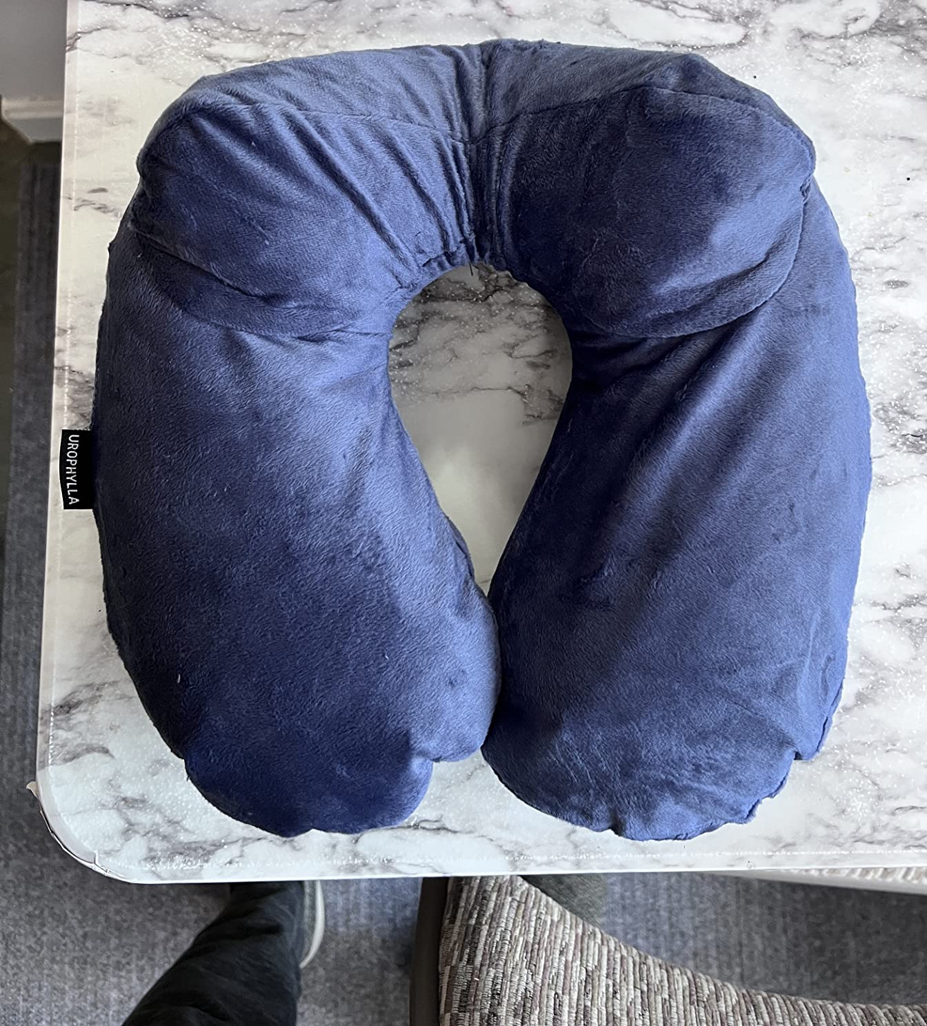A blue travel neck pillow, the UROPHYLLA Inflatable Travel Pillow, displayed on a table for a product review.